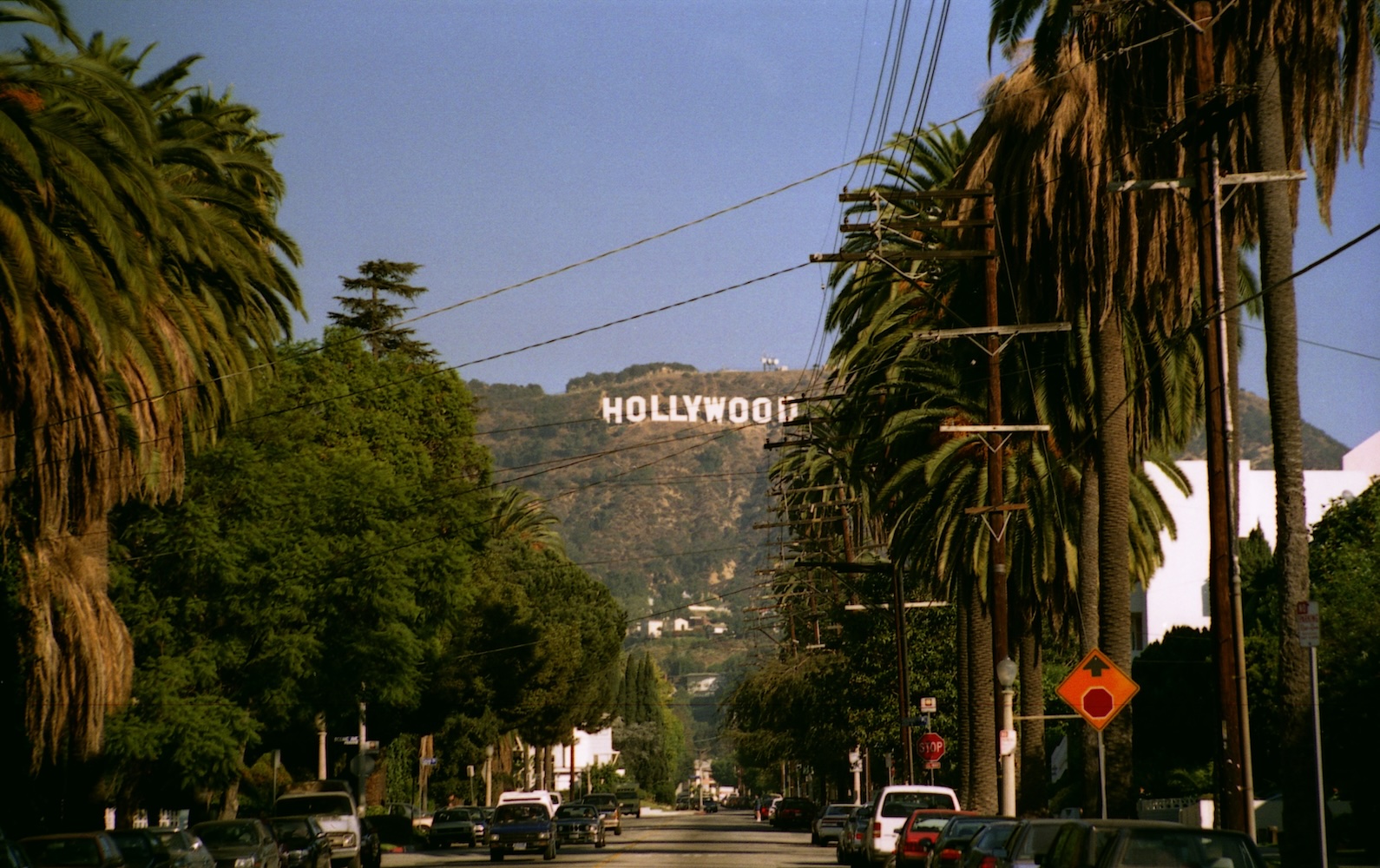 View of the Hollywood sign in the hills from a street.